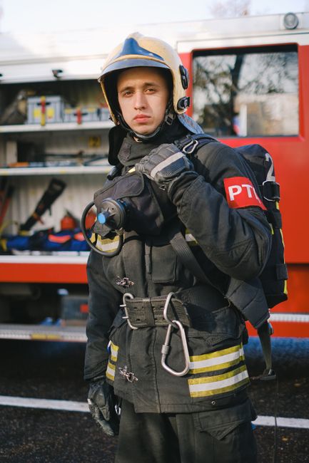 pexels-photo-5964974-5964974 Firefighter in full uniform holding equipment, standing in front of a fire truck.